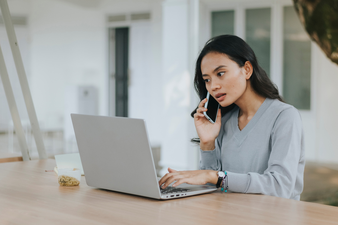 Woman on a Phone Call While Working on a Laptop